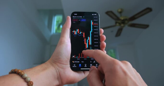 Stock trader using smart phone app analyzing financial data crypto stock market price bitcoin on smartphone checking online trading platform application on home office interior. Cryptocurrency concept