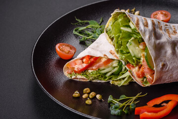 Delicious fresh shawarma with tomatoes, peppers, cucumber on a dark concrete background