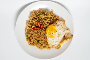 Foto op Canvas Top view of Indomie fried noodles (mi goreng) with sunny side up egg. Tasty food isolated in white background. © Wildan