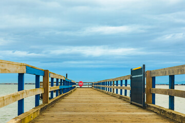 Fototapeta na wymiar Wooden pier with sea and blue sky at the background. A wooden pier or jetty heading toward the horizon