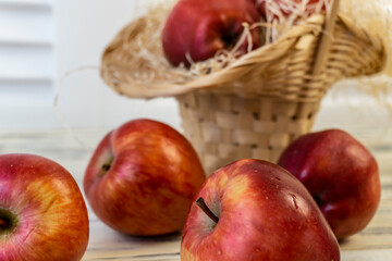 Red apples in a basket and on a wooden table
