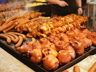 Slightly blurred pork knuckles, skewers and sausages on a huge grill, on the Krakow christmas market.