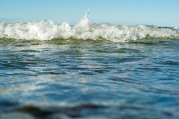 Carefree ocean waves. Blue water surface with small waves. Background on the theme of holidays and vacations at sea with the family. Water with white foam in soft focus on a bright sunny day.