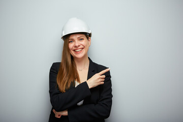 Smiling woman architect in safety helmet pointing finger at side. Isolated female portrait. - obrazy, fototapety, plakaty