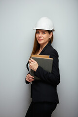 Isolated profile portrait of woman engineer wearing safety helmet and black suit holding books or business paper.