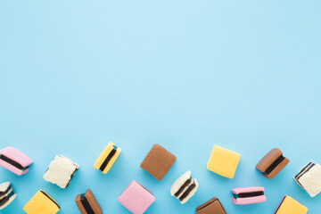 Colorful jelly gummy candies on light blue table background. Pastel color. Sweet snack. Closeup. Empty place for text. Top down view.
