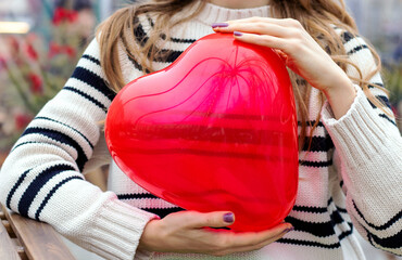woman sitting in on table with paper hearts garland in one hand using smartphone with another,girl hugging red balloon heart shape.celebrate love valentine day coffee shop inside transparent balloon