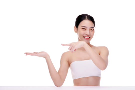 Beautiful Asian woman wearing spa clothes smile and pointing finger to an empty palm isolated on yellow background studio portrait.