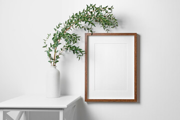 Artwork frame mockup on white wall with eucalyptus plant
