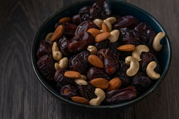 Obraz na płótnie Canvas dates and nuts in a bowl on a dark background
