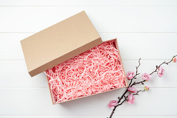 Shredded pink paper packing material texture in a craft box with sakura branch, mockup design