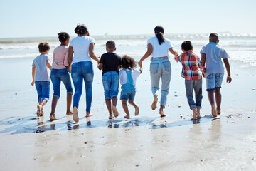 Big family, beach walk and water for vacation, sunshine and bonding with interracial diversity by waves. Happy family, mother and holding hands for solidarity, care and love on holiday by sea
