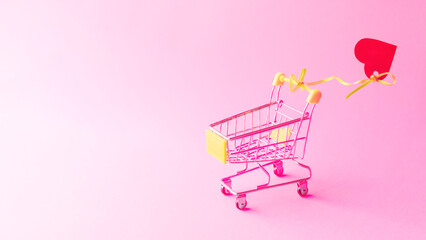 Shopping trolley with heart on pink background. Promotion and shopping template.Valentine's Day.copy space, toned
