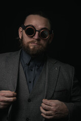 charismatic man in a classic suit and steampunk goggles on a black background stylish Portrait