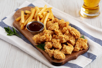 Homemade Popcorn Chicken with BBQ Sauce on a Rustic Wooden Board, side view.