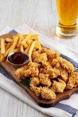 Homemade Popcorn Chicken with BBQ Sauce on a Rustic Wooden Board, side view.