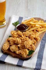 Homemade Popcorn Chicken with BBQ Sauce on a Rustic Wooden Board, side view.