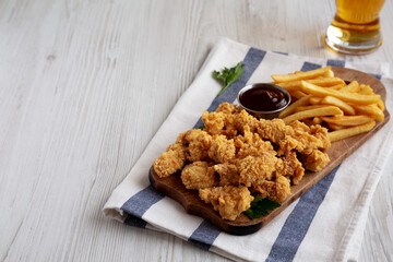 Homemade Popcorn Chicken with BBQ Sauce on a Rustic Wooden Board, side view. Space for text.