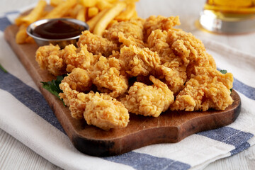 Homemade Popcorn Chicken with BBQ Sauce on a Rustic Wooden Board, side view. Close-up.