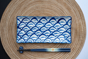 Japanese or Chinese table setting with traditional table mat and sushi plate with back and white background. Eating and dining concept. Flat lay, top view and copy space.