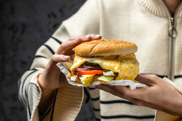 the girl is biting a burger with melted cheese, Fast food take away copy space