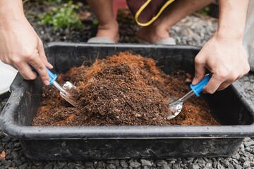 Mixing soil and fertilizer, planting plants into a black tray, preparing to grow seedlings.