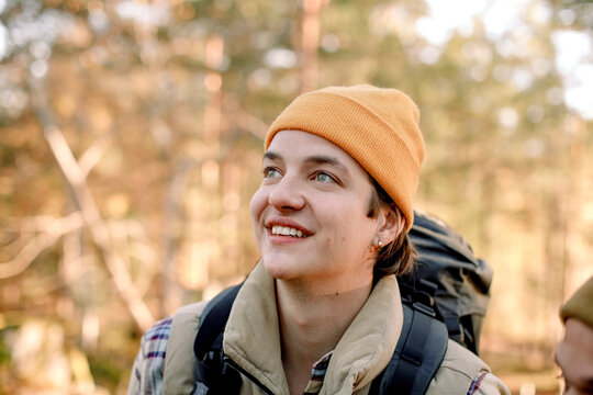 Young smiling man wearing knit hat looking away during hiking