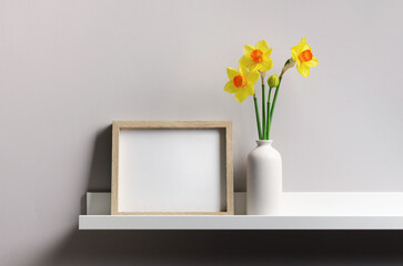 Wooden frame mockup with narcissus flowers over grey wall, mockup for artwork presentation