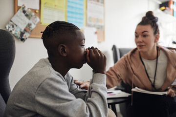 Depressed male student listening to advice from mental heath professional in school office