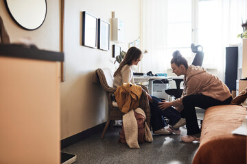Non-binary physiotherapist examining leg of female student in school office