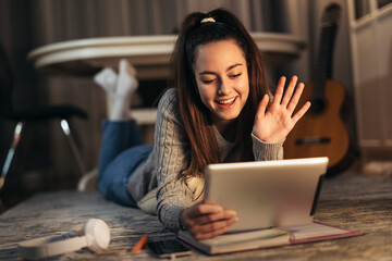 Happy young teen girl using digital tablet to make video call