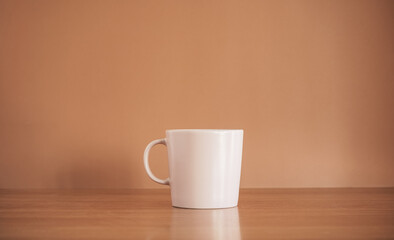 Pink coffee mug on wood table with brown background