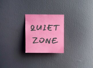 Wall with pink note written QUIET ZONE, means controlling noise and improving privacy to focus on study like workplace library, hospital or meditation area where mobile phones are banned
