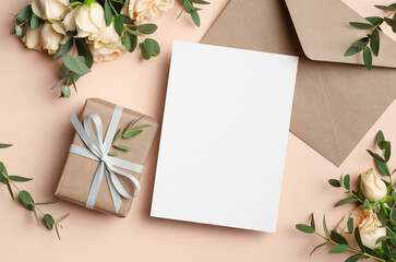 Greeting card mockup with fresh roses flowers and gift box, blank card with copy space