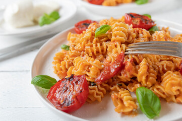Pasta with tomato mozzarella sauce, parmesan cheese and basil on a plate