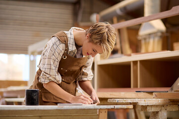 Female Apprentice Working As Carpenter In Furniture Workshop