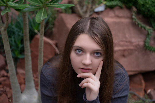 Portrait of happy beautiful young science student. Youn girl in a greenhouse with tropic plants. She is studiing plants