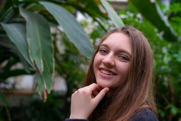 Portrait of happy beautiful young science student. Youn girl in a greenhouse with tropic plants