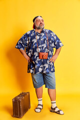 Portrait of fat mature man in stylish shirt posing with proud look over bright yellow studio...