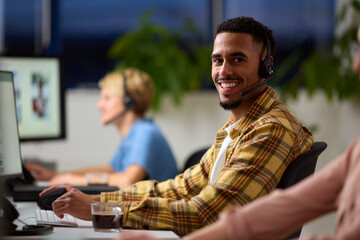 Portrait Of Business Team Wearing Headsets Working Late At Customer Support Centre