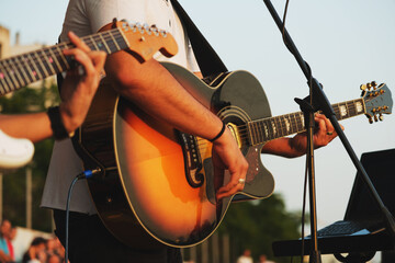Close up shot of guitarist playing a guitar on a concert.