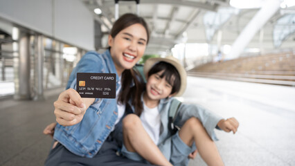 Asian Family mother and son shopping travel in holiday tourism  with a credit card in the city.Young family standing with suitcases holding empty credit card, over white background. Travel credit card
