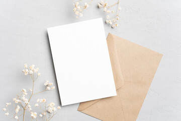 Blank invitation or greeting card mockup with flowers and envelope, wedding card flat lay