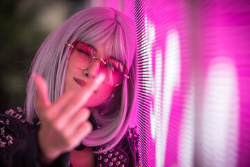 Image of a beautiful young woman posing against a led panel.