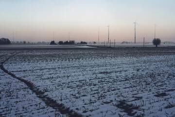 wind farm in brandenburg with snowy fields at dawn