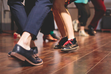 Dancing shoes of young couple dance retro jazz swing dances on a ballroom club wooden floor, close up view of shoes, female and male, dance lessons class rehearsal