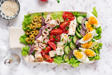 Healthy cobb salad with ham, cucumber, tomato, olives, feta cheese and eggs. Ketogenic lunch. Top view, overhead