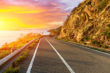 Asphalt highway and mountain scenery at sunset by the seaside