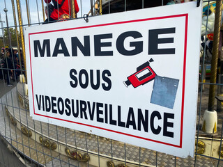 French "merry-go-round under surveillance" sign with a cctv camera