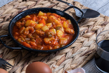 Pisto manchego (Manchego ratatouille) with red and green peppers, courgette and onion. Red wine and eggs. Typical and traditional Spanish food.
